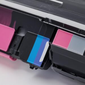 Close-up view comparing a toner cartridge (filled with fine black powder) on one side and a colorful ink cartridge (with visible liquid ink) on the other, highlighting their distinct contents.