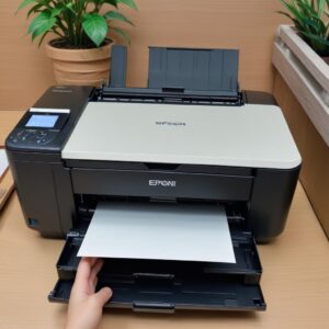 Gambar printer Epson L3210 yang baru saja selesai di-reset, lampu indikator menyala hijau normal, dan sedang mencetak selembar kertas dengan senyum lega di wajah.
