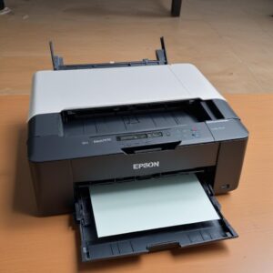 Printer Epson L3210 yang berfungsi normal dengan lampu indikator hijau menyala, mencetak dokumen berwarna dengan mulus. Di latar belakang, terlihat orang tersenyum puas.