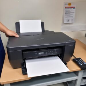 Tangan seseorang memegang suntikan (tanpa jarum) dengan cairan pembersih, bersiap untuk membersihkan print head printer Epson L3210 secara manual. Terlihat bagian dalam printer yang terbuka.